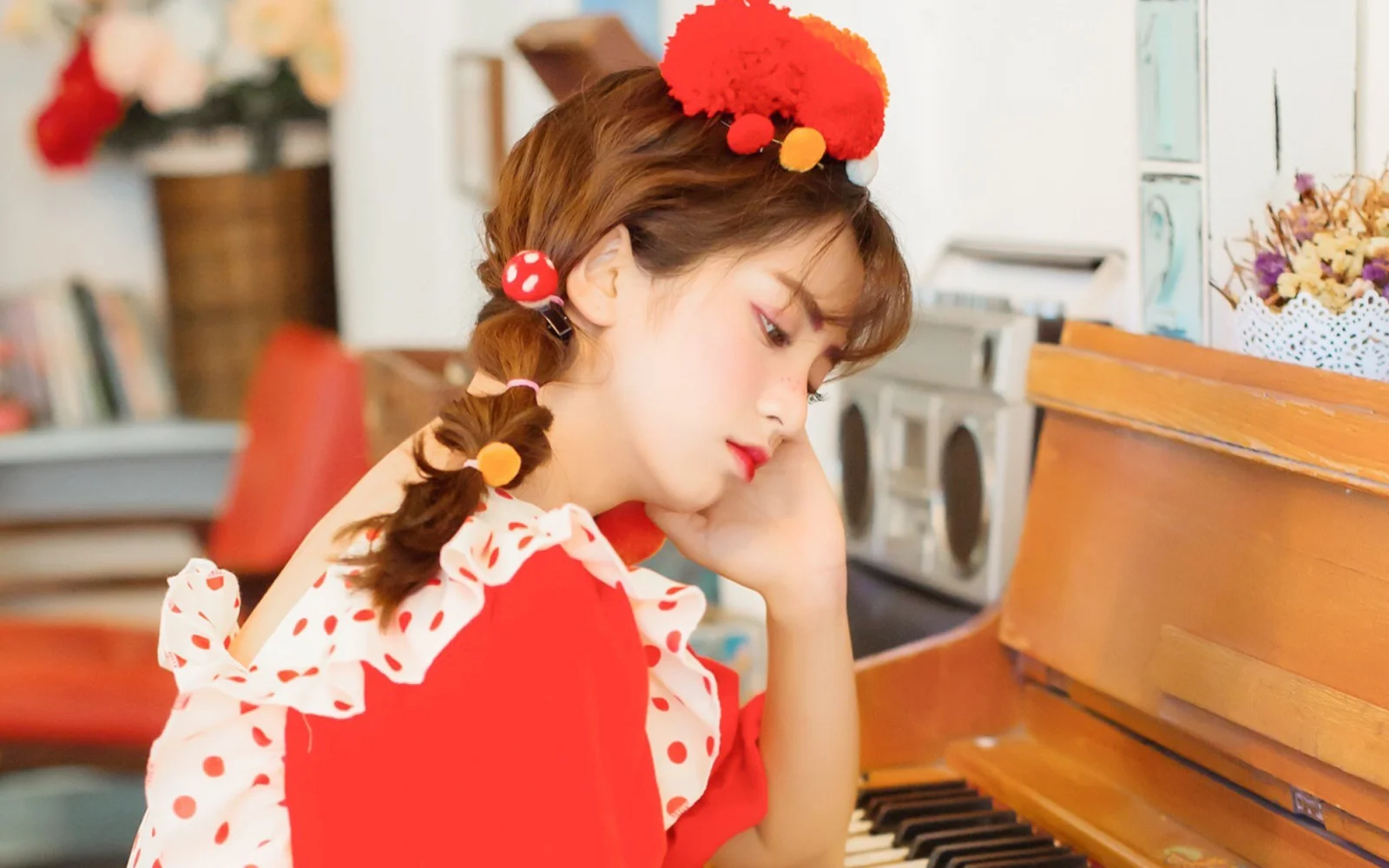 赤い服を着た女性が、柔らかな室内光の中でピアノのそばに寄りかかっている。