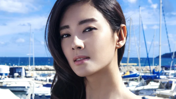 一名成年女性在蓝天与海港帆船背景前的近距离肖像。