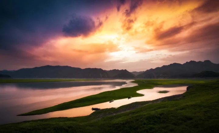 晚霞映照着群山、湖泊与蜿蜒河道，构成宁静的自然风景。