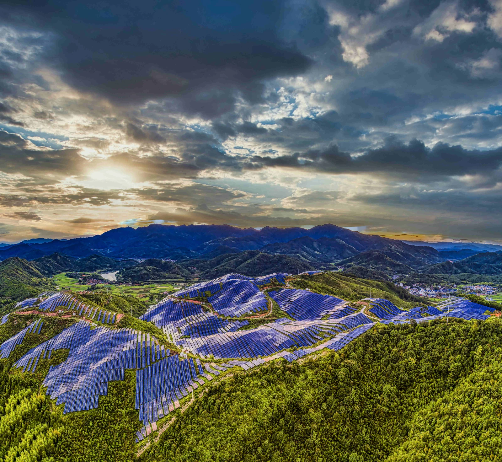 層疊的山地梯田與綠色森林延伸在壯闊的多雲天空下。