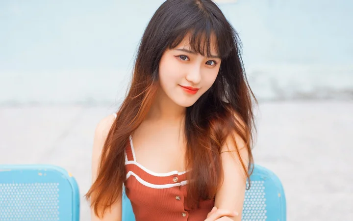 一位长发女子坐在蓝色椅子上面向镜头微笑。