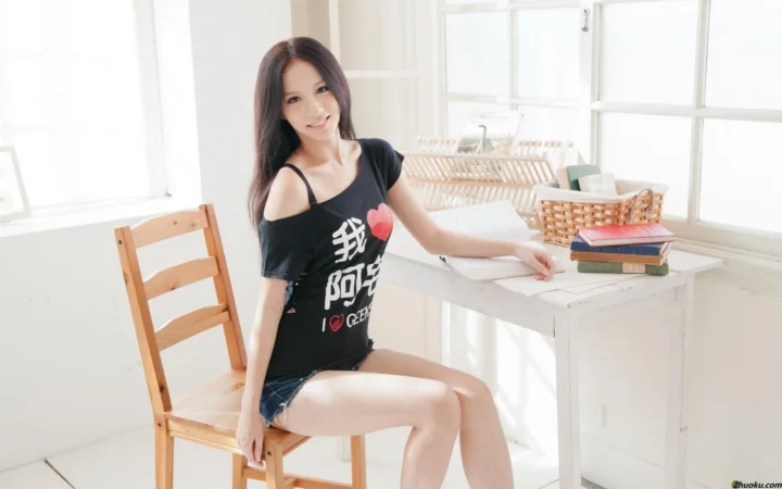 一名成年女性坐在木椅上，身旁是明亮窗边的白色书桌。