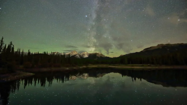 银河横跨夜空，远处山脉与湖面倒映出星光。