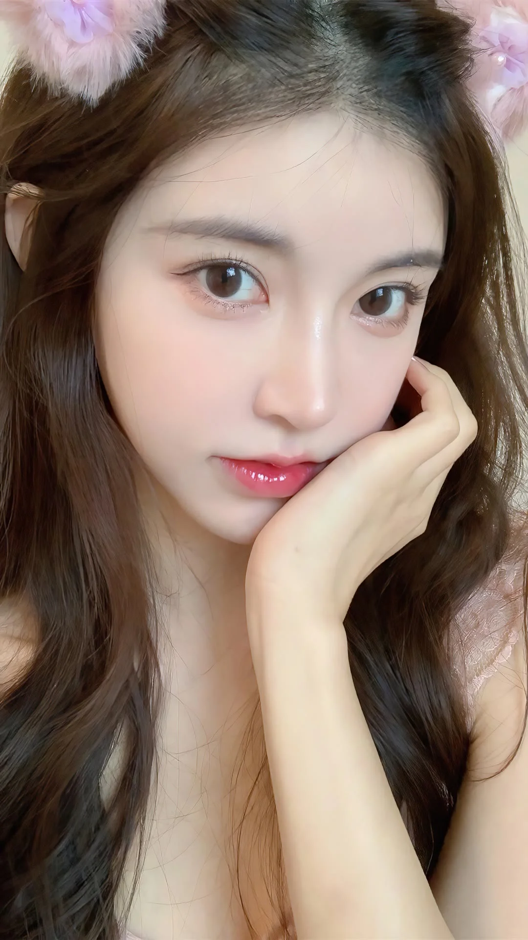 긴 머리의 여성이 손으로 볼을 받친 채 카메라를 바라보는 부드러운 클로즈업 인물 사진입니다.