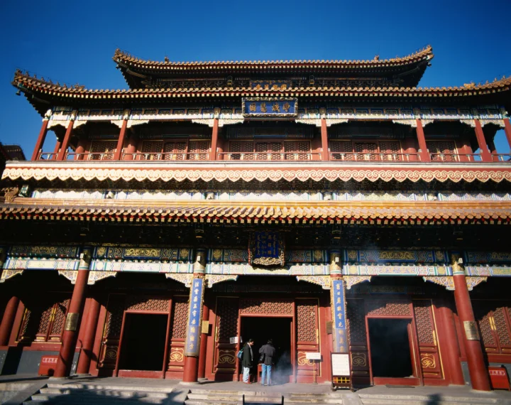 蓝天下，一座红柱金饰的传统寺庙建筑正面占据画面。