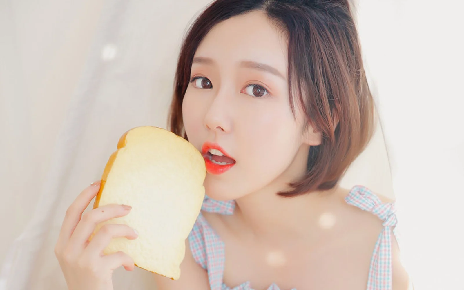一位女性近距离手持面包并望向镜头。