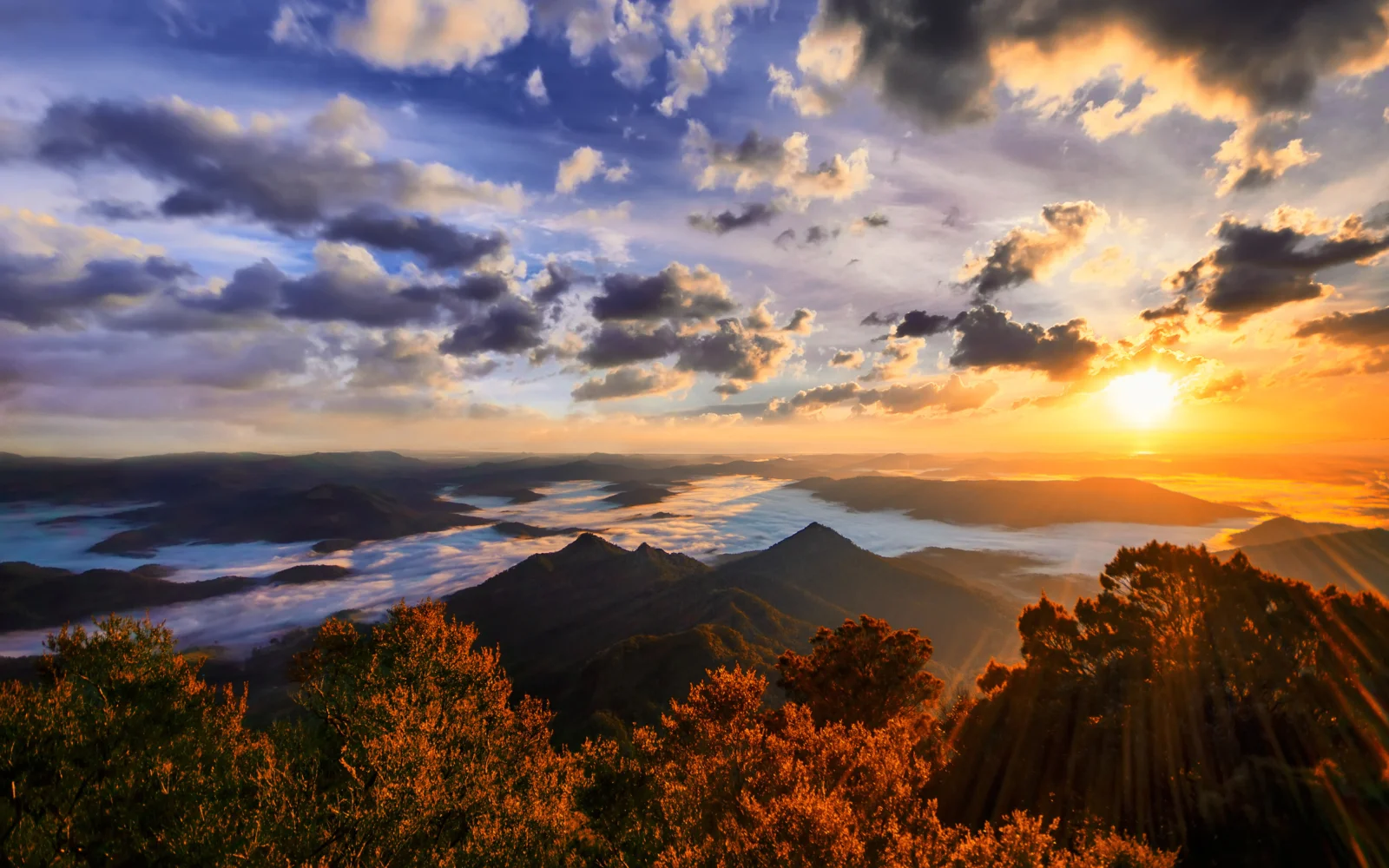 夕阳照耀着层叠山脉、湖泊和绚丽云层。