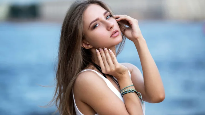 青い水面を背景に成人女性がポートレートのポーズを取っている。