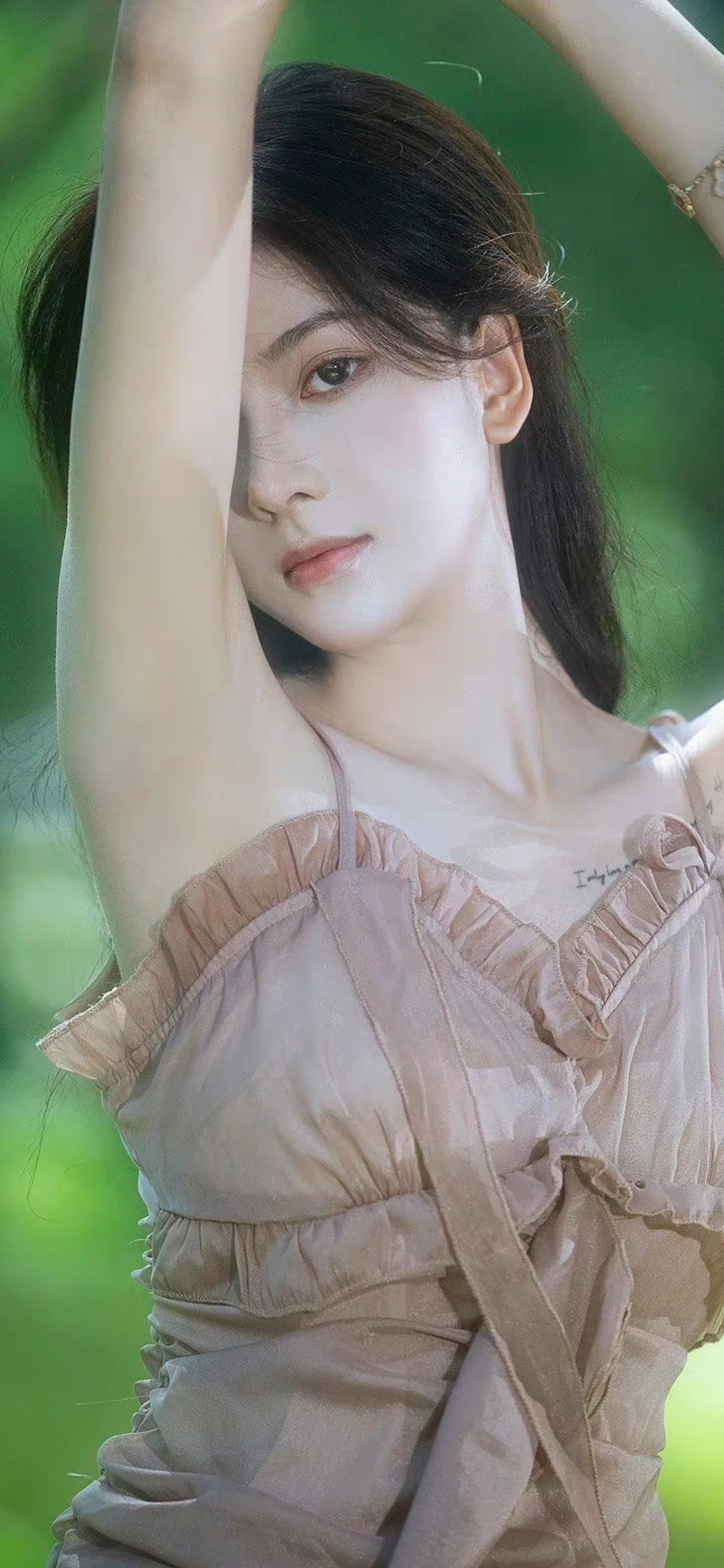 一名成年女性身穿浅色褶皱上衣，在绿色背景前抬起手臂面向镜头。