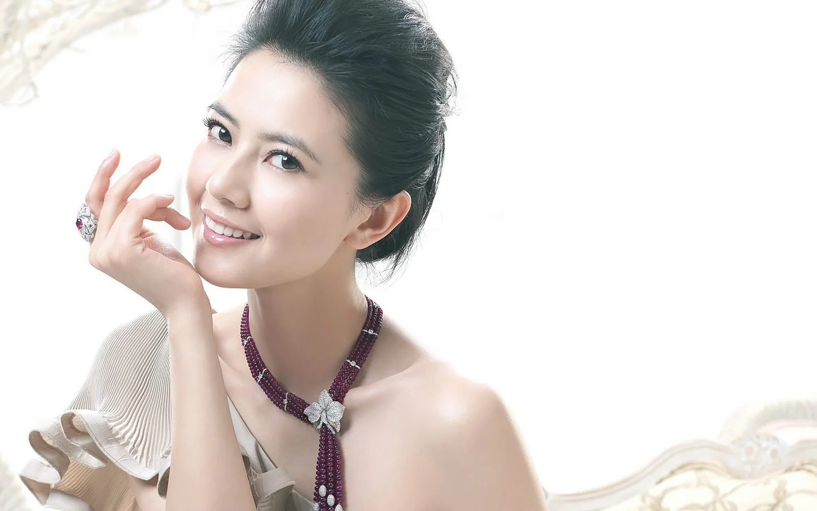 一位成年女性在明亮背景前微笑展示优雅肖像与项链。