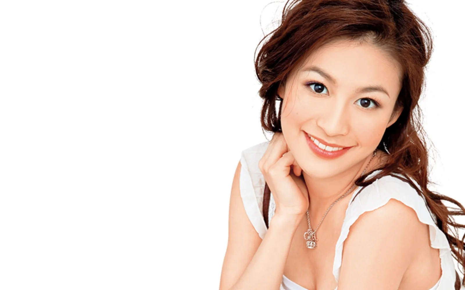 흰색 배경 앞에서 성인 여성이 카메라를 향해 미소 짓고 있다.