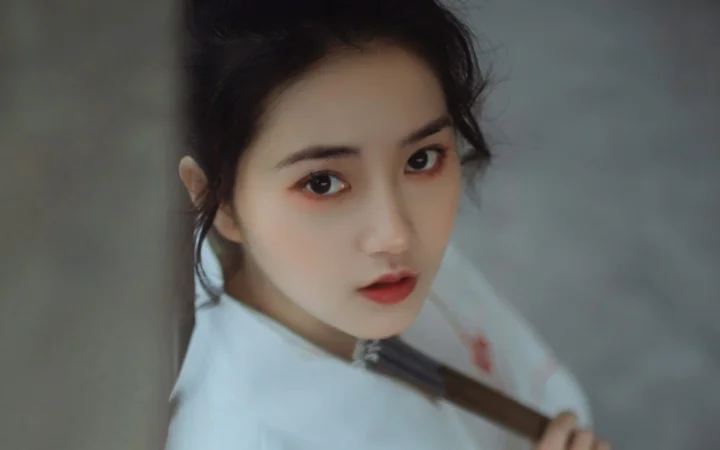 一名女性近距离看向镜头，背景为柔和的灰色调。