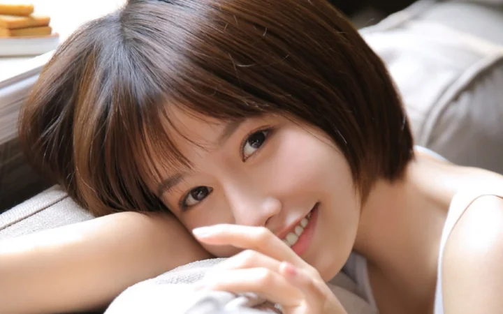 一位留著棕色短髮的女性靠在柔軟表面上微笑看向鏡頭。