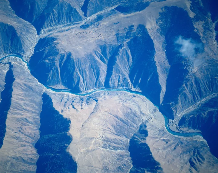 俯瞰群山峡谷与蜿蜒河流交汇的自然景观。