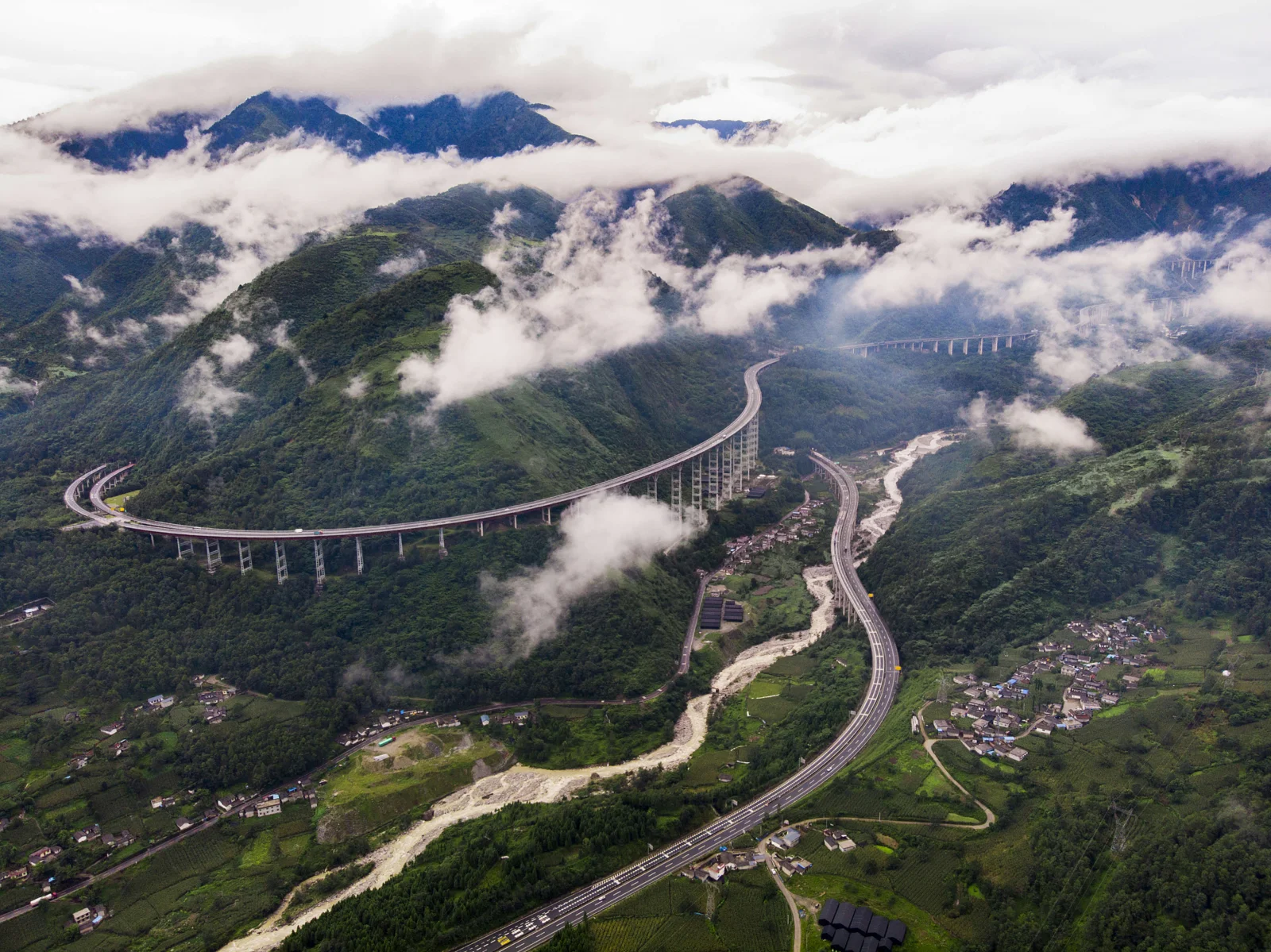 雲霧環繞的青山之間，一條蜿蜒公路穿過山谷與村莊。
