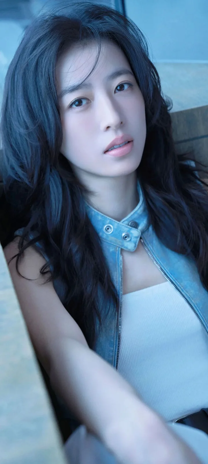 一名長髮女性身穿藍色無袖夾克，面向鏡頭拍攝肖像。