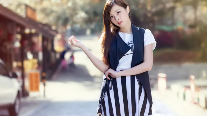 一名成年女性穿着黑白条纹裙站在户外街道上。