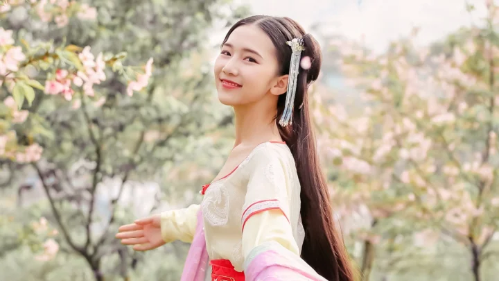 一位身穿传统服饰的女子站在繁花掩映的户外花园中。