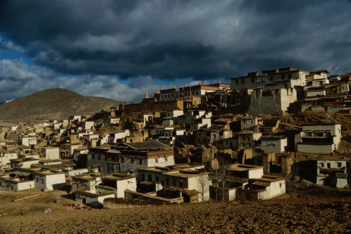 山坡上的古老村落建筑沐浴在暴雨云层下的昏暗光线中。