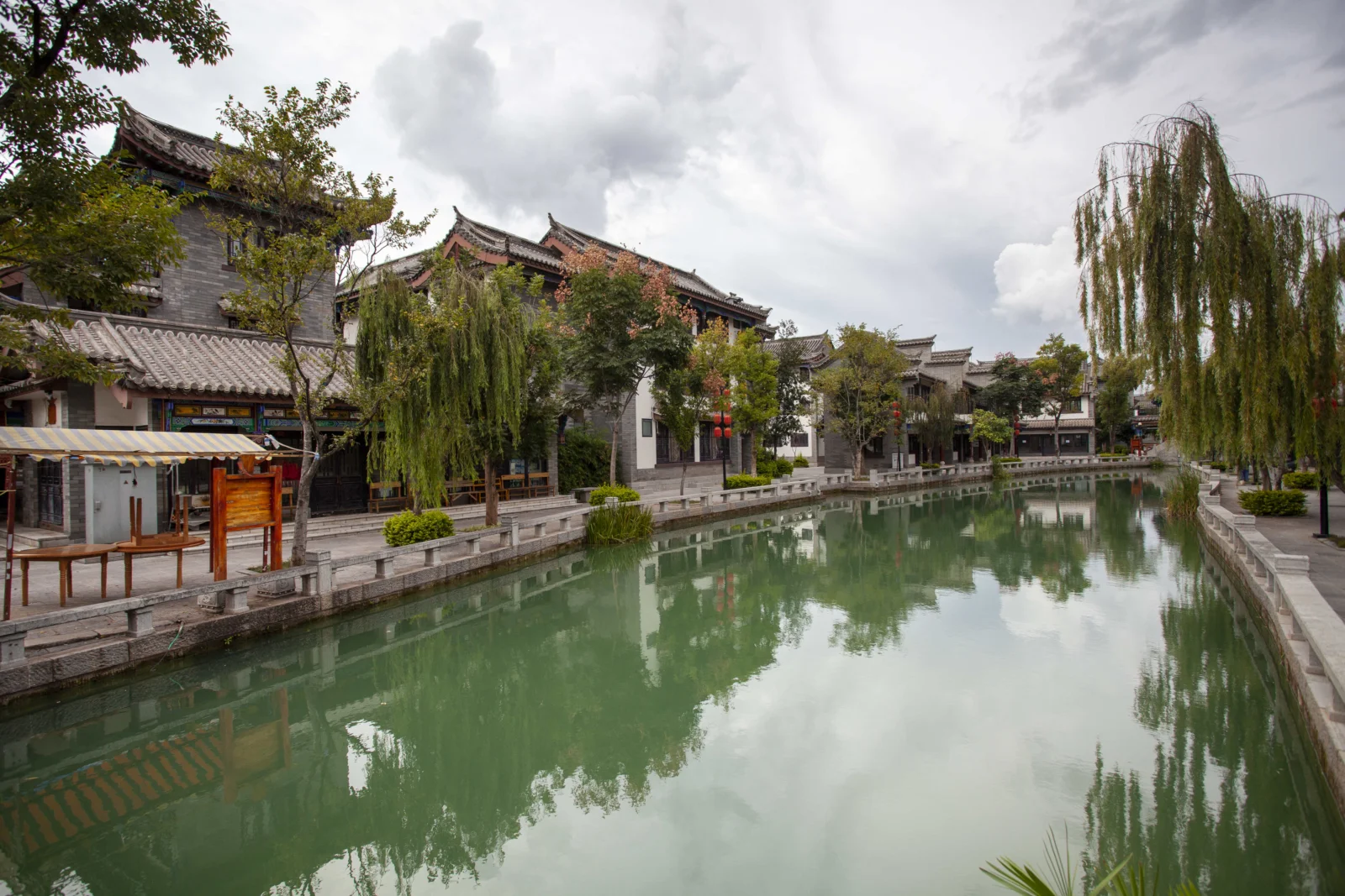 伝統的な建物と柳、水路に映る景色が静かな都市の水辺を作っている。