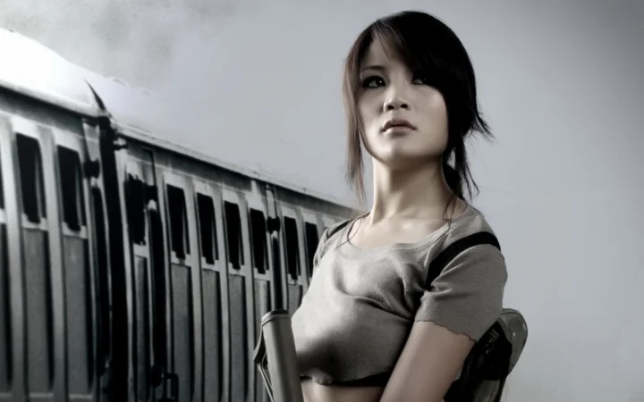 성인 여성이 열차 객차 옆에 서 있는 그레이스케일 장면입니다.