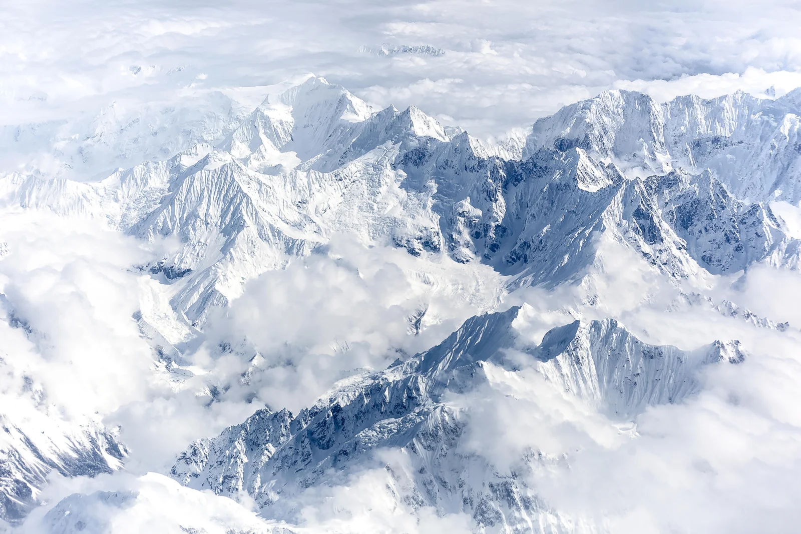 连绵的雪山从云海中拔地而起，覆盖着冰雪与雾气。