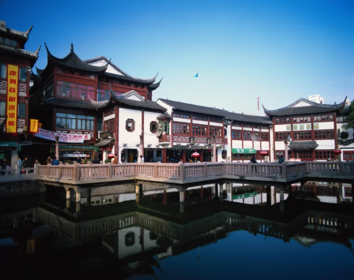 蓝天下，传统中式建筑沿着运河铺展，桥梁与倒影构成宁静的城市风景。