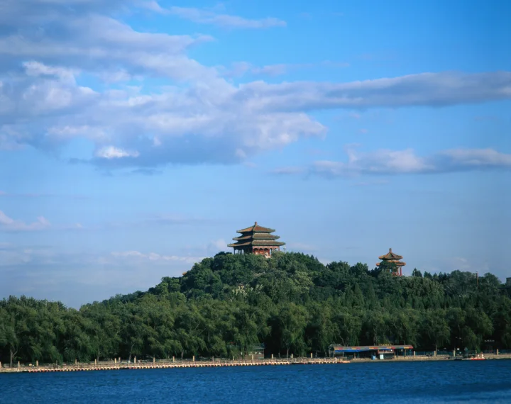 蓝天下的湖泊、森林与山丘上的传统亭阁构成宁静的自然风景。
