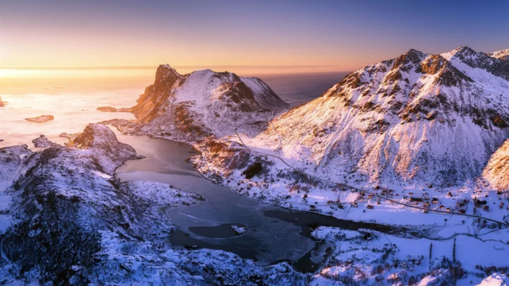 夕阳映照着被积雪覆盖的群山、湖泊与海岸。