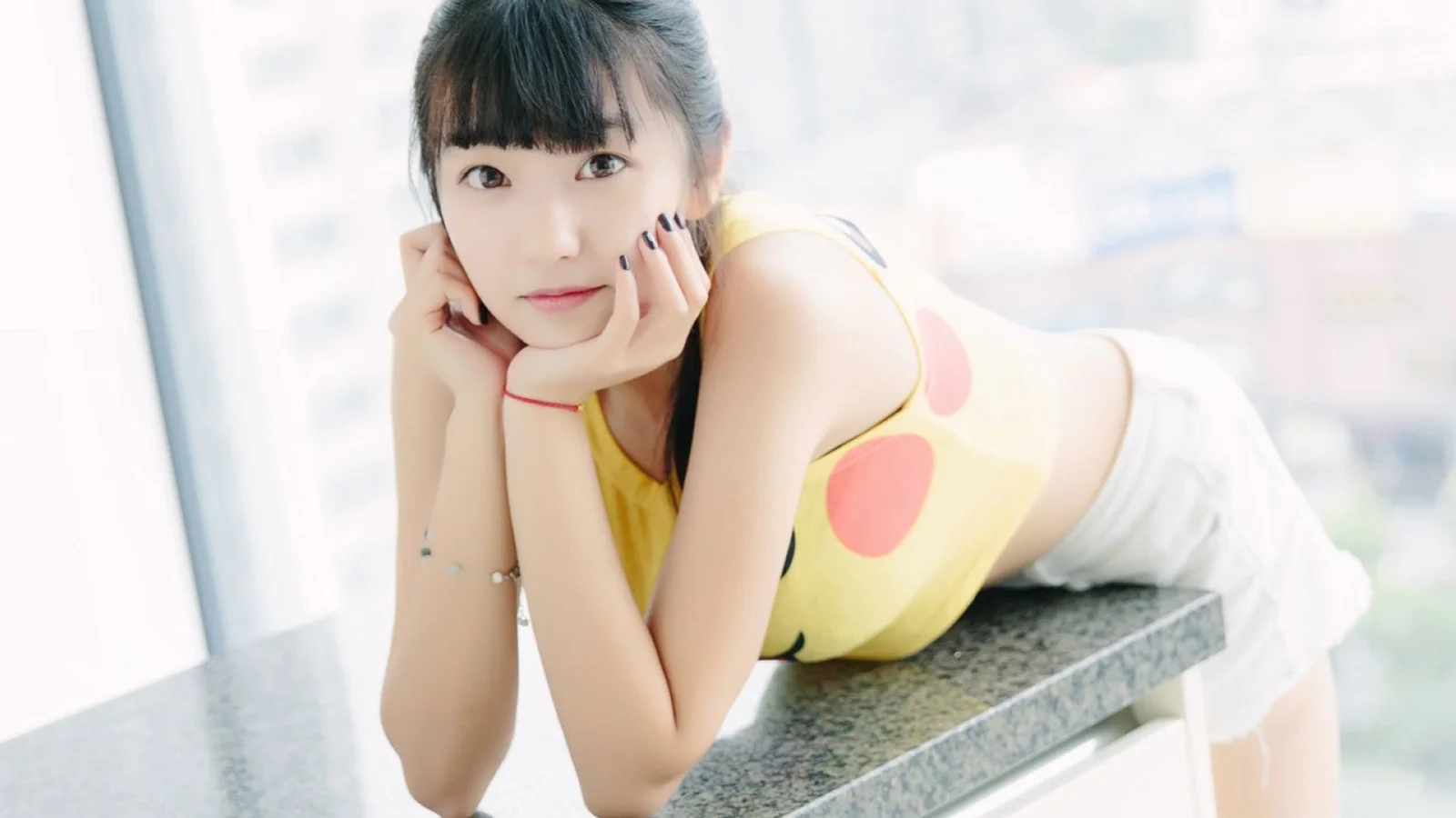 一名女性在明亮的窗边室内俯身看向镜头。