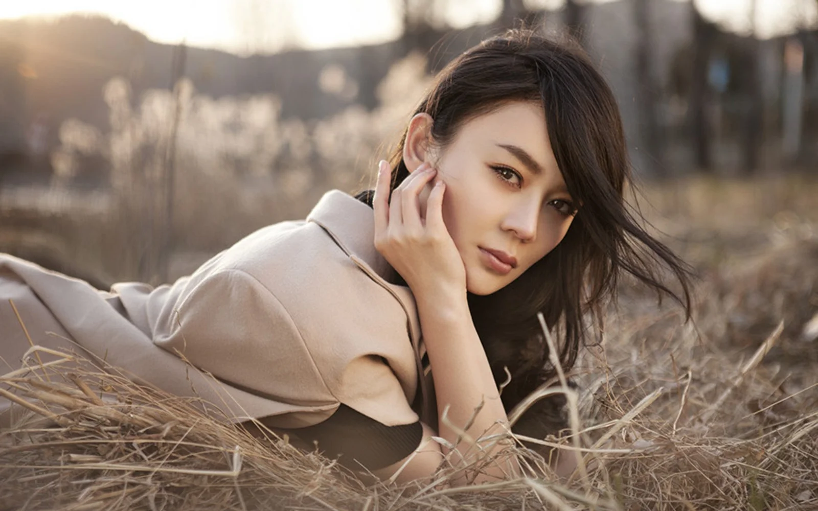 一名成年女性躺在秋日干草中，侧身看向镜头。