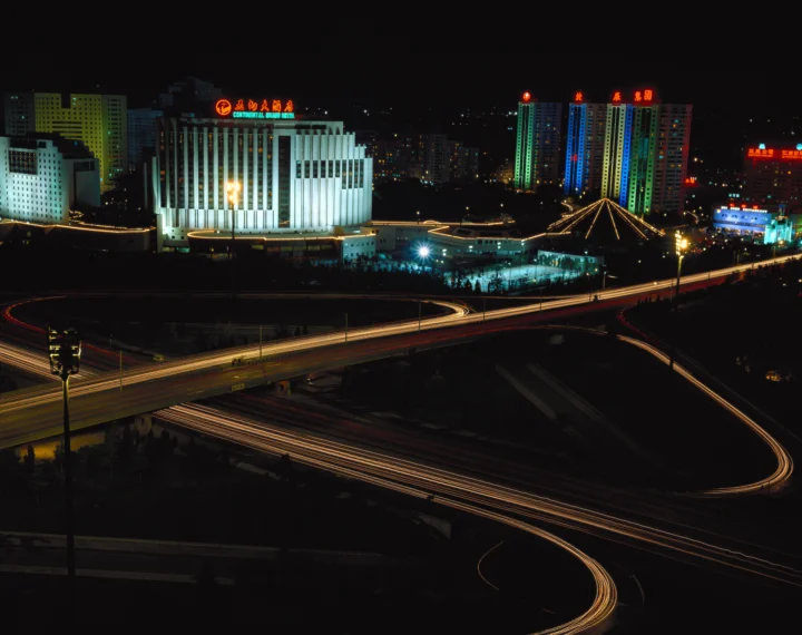 夜色中的城市建筑与立交道路被霓虹灯光映亮，车流留下蜿蜒的光轨。