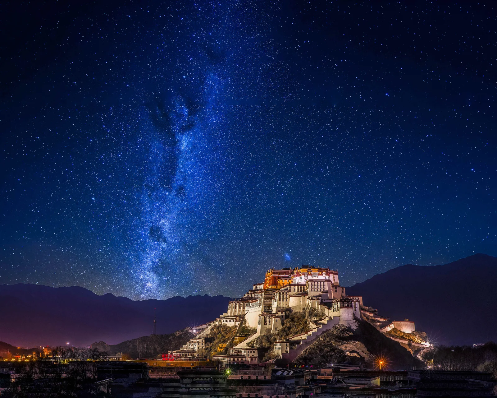 夜空中的银河和繁星映照着山峦间的宫殿建筑。