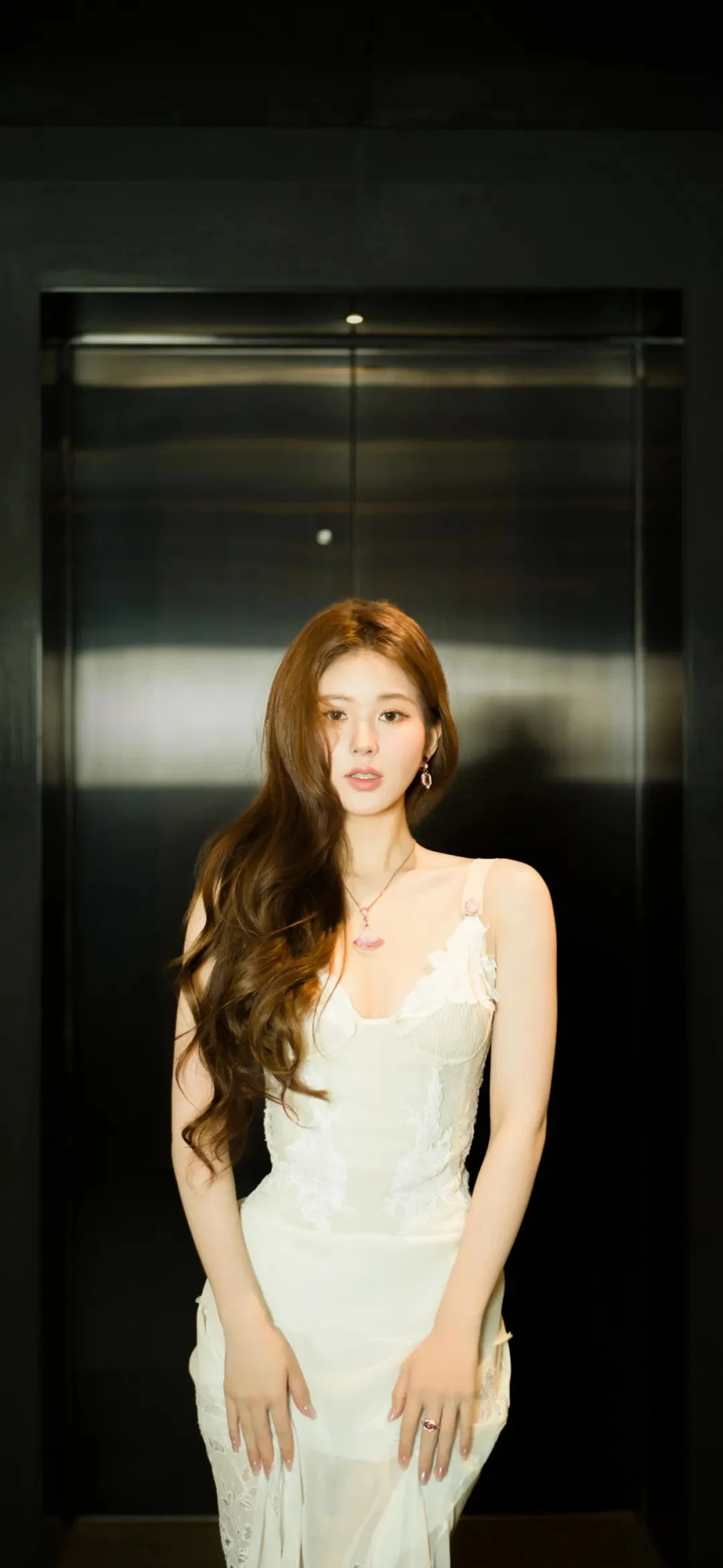白いドレスを着た成人女性がエレベーターの中に立っています。