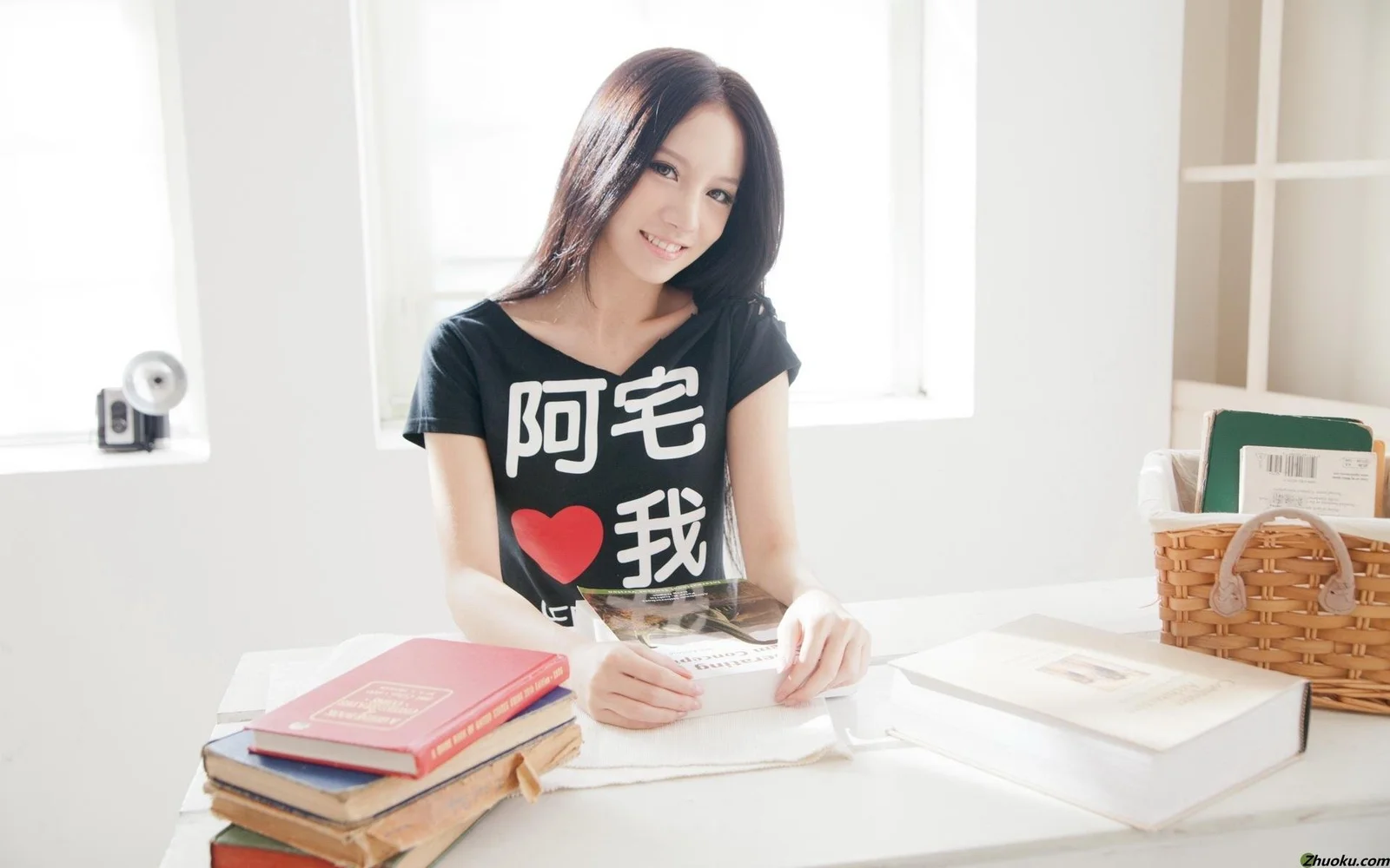 一名成年女性坐在明亮的室内书桌前，桌上放着书本和纸张。