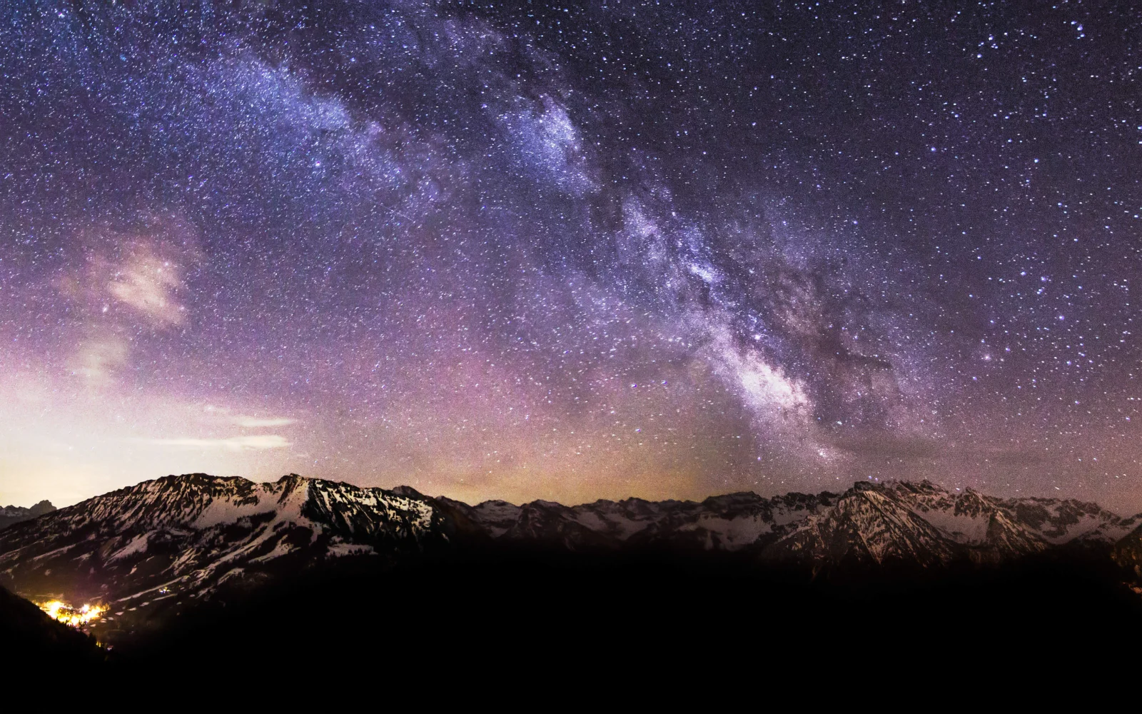 璀璨的银河横跨夜空，下方是被星光映照的雪山山脉。