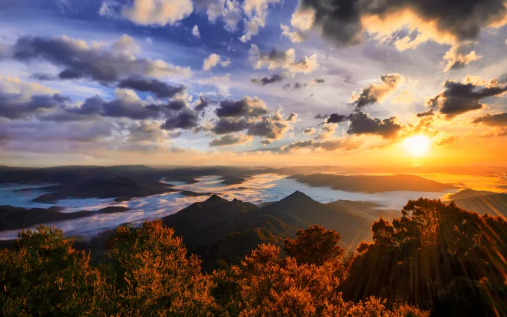 夕阳照耀着层叠山脉、湖泊和绚丽云层。