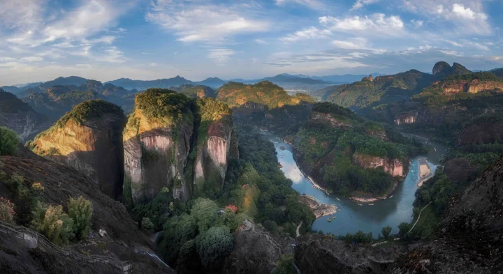 群山、森林与蜿蜒河流在蓝天白云下展开壮丽全景。