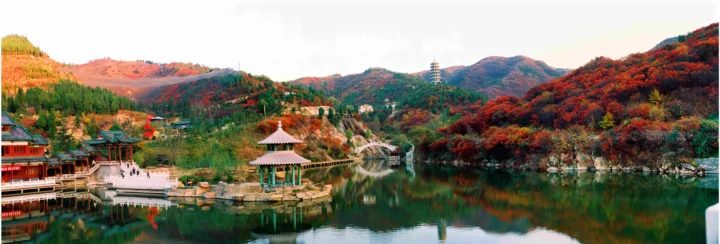 群山、森林与湖泊构成一幅秋色全景，湖畔可见传统亭台建筑。