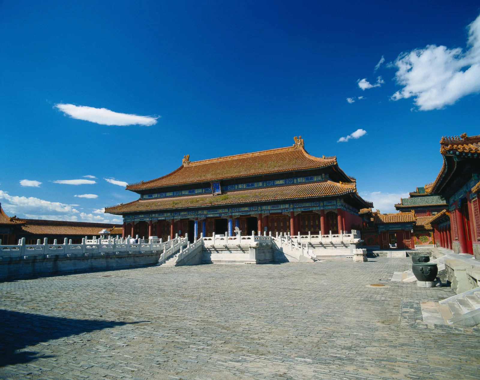 蓝天下的古建筑宫殿坐落在宽阔的石砖庭院中。