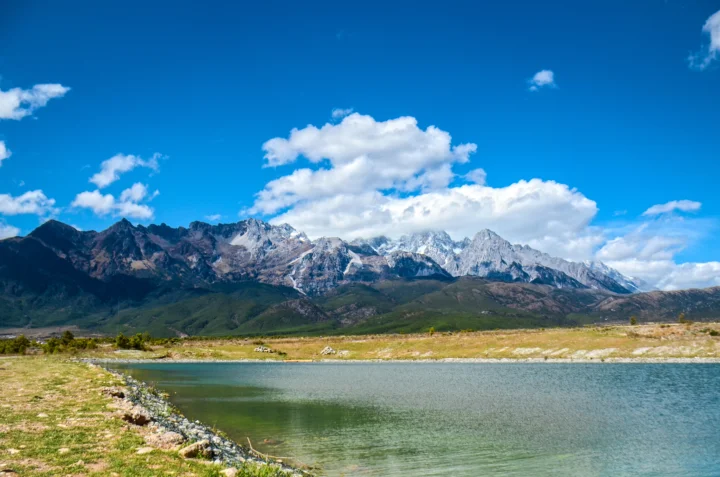 蓝天下的雪山、湖泊与白云构成开阔的自然风景。