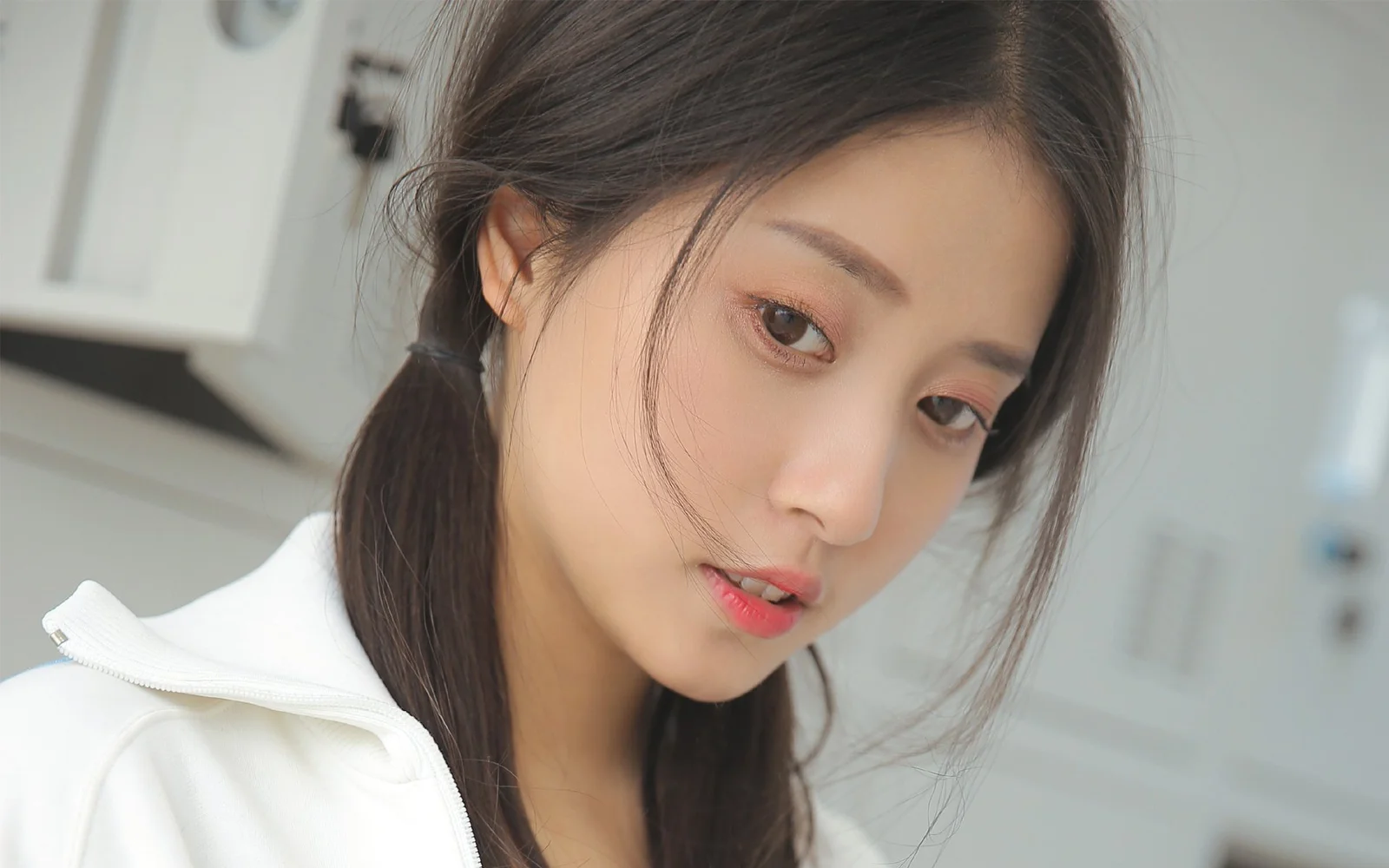 白いトップスを着た成人女性が、室内で横顔を近距離から写したポートレートです。
