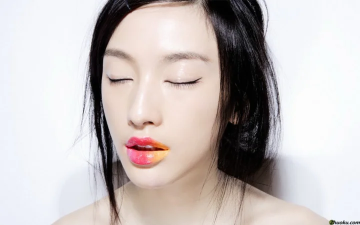一名闭着眼睛的女性面部特写，嘴唇呈现鲜艳的红橙色妆容。