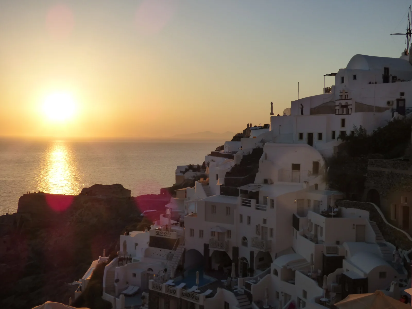 夕陽映照著海面和層疊的白色海濱建築。