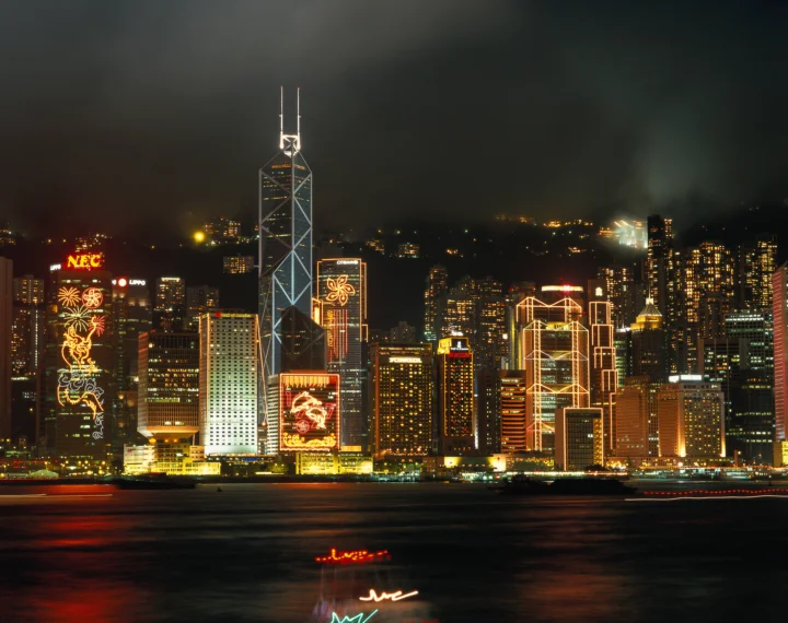 夜色中的城市天际线沿着水面展开，高楼灯光倒映在波光中。