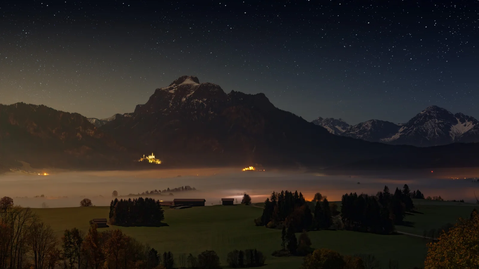 夜空下的高山、湖泊与雾气笼罩的田野构成宁静的自然风景。