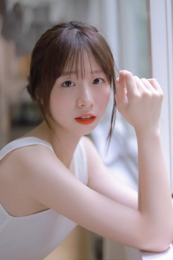 一位成年女性在窗边面对镜头，柔和的室内光线映照出她的面容。