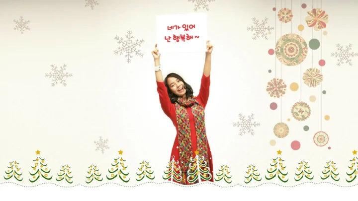 빨간 옷을 입은 여성이 한글 문구가 적힌 표지판을 들고 눈송이와 알록달록한 장식, 크리스마스트리 무늬 사이에 서 있습니다.