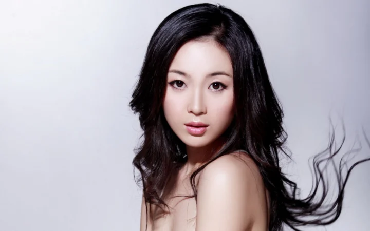 一名黑发女性在浅灰背景前面向镜头摆姿势。