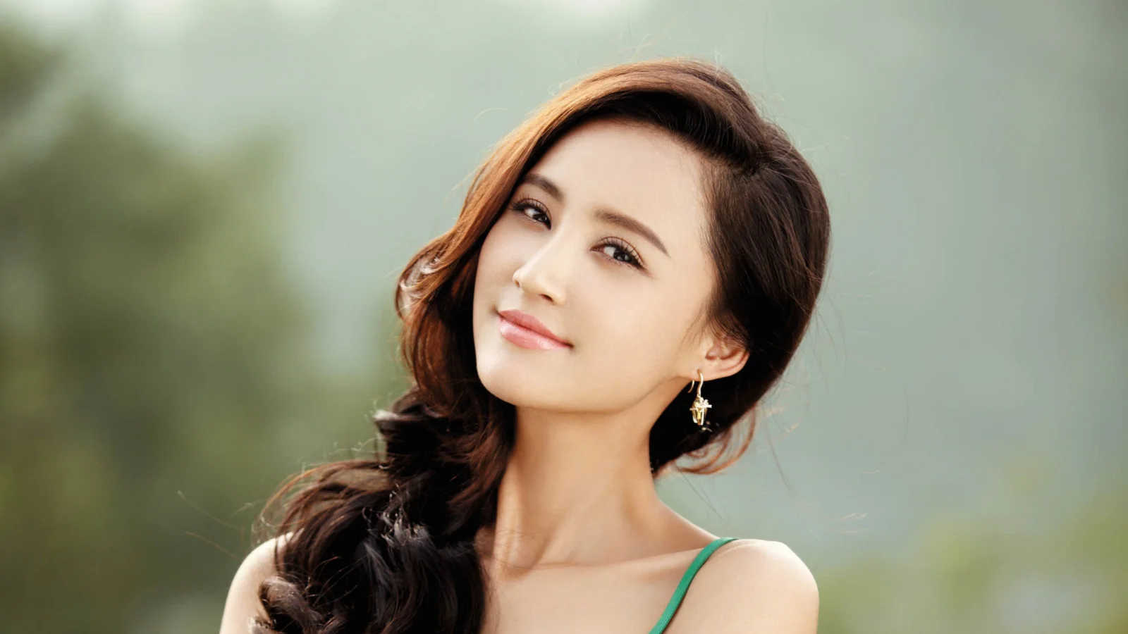 一位长发女性在柔和虚化背景前微笑看向镜头。